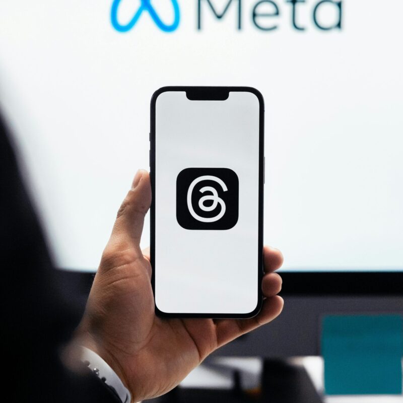 Close-up of a person holding a smartphone displaying Meta's threads logo.